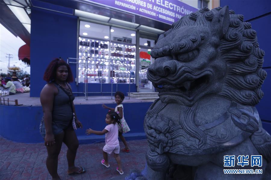 5月1日，在多米尼加共和国首都圣多明各，一名市民带着孩子游览“中国城”。
