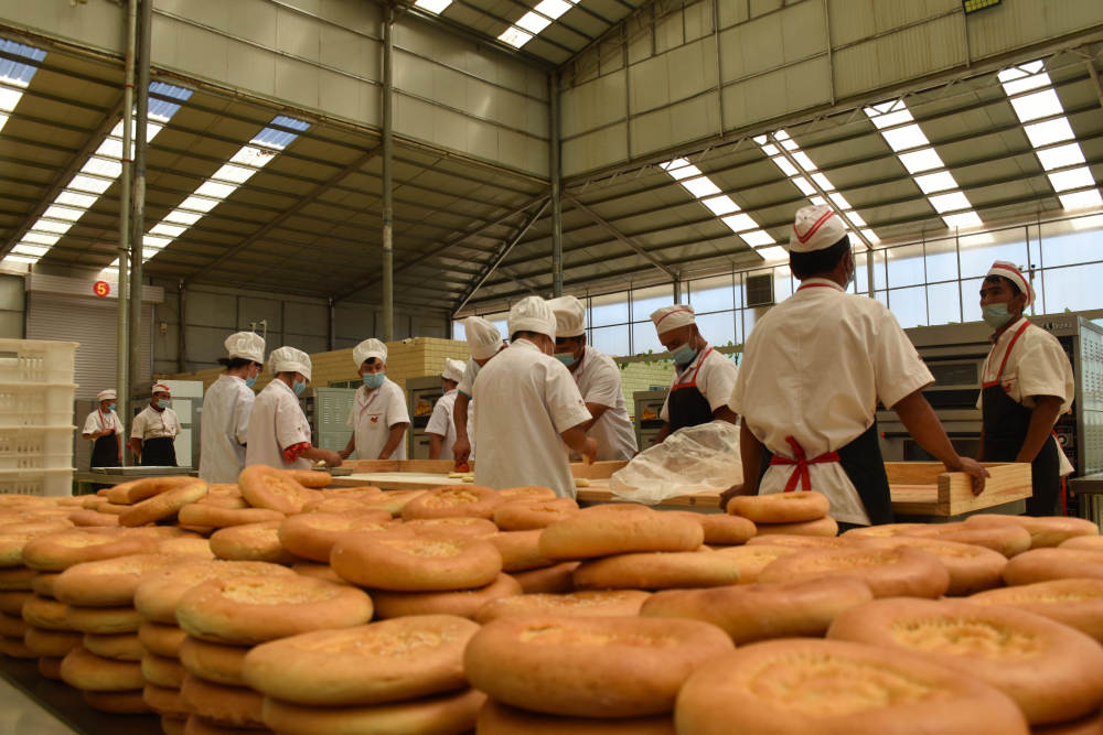 7月7日,工人在新疆喀什地区伽师县馕产业园制作馕.