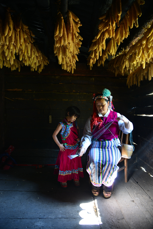 2014年11月7日,云南怒江州贡山县捧当乡怒族妇女在纺线,一小女孩在
